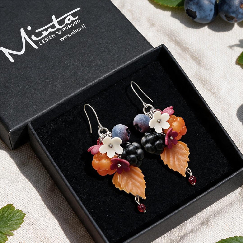 Berry Forest Earrings presented in a gift box, surrounded by natural linen fabric, fresh cloudberries, blueberries, and autum leaves. Handmade in Finland by byMinta.