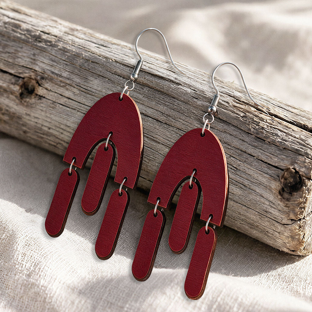 Brown Fluttering Hems plywood earrings made in Finland, photographed on a vintage book in natural sunlight