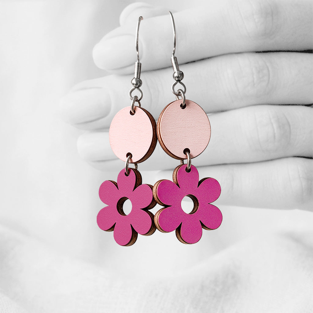 Light pink & Raspberry JytäRetro plywood earrings made in Finland, photographed against a black and white background of a hand.