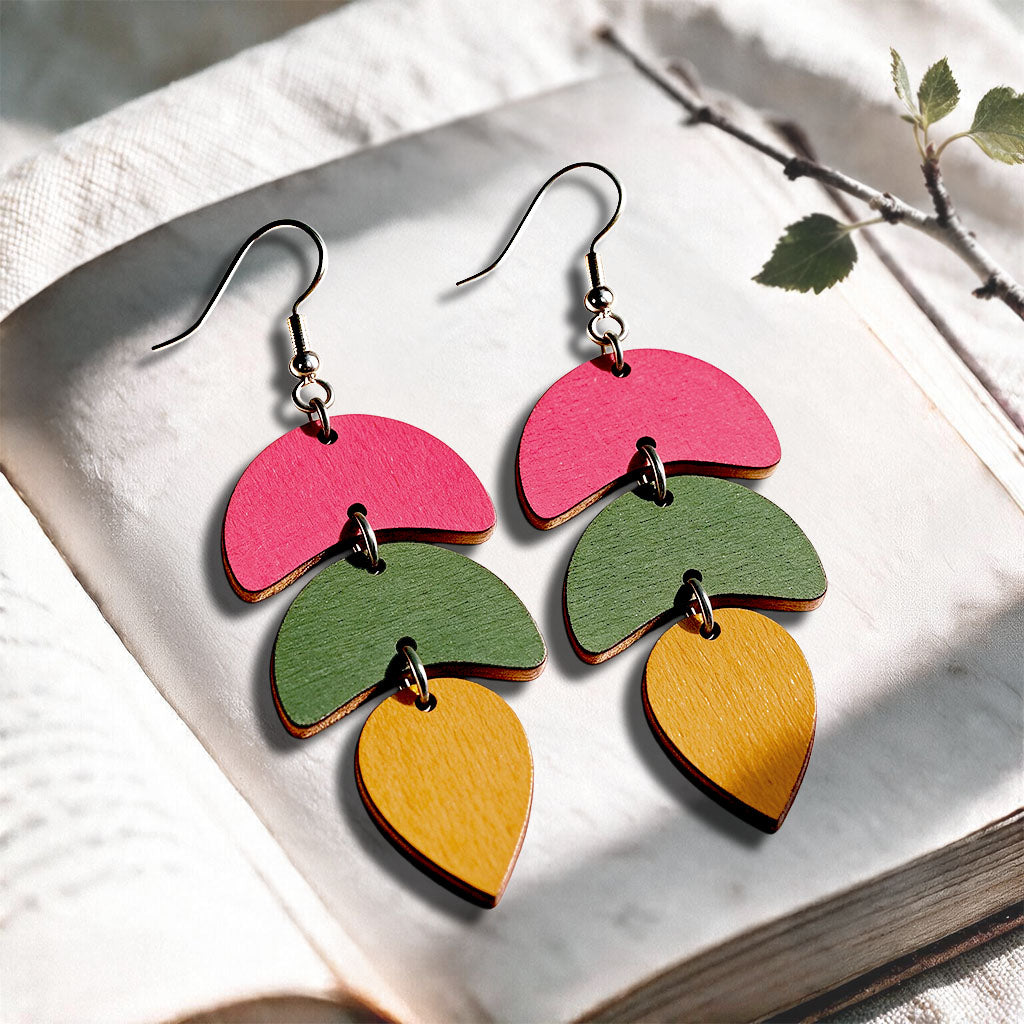 Lion, green and raspberry Echo plywood earrings made in Finland, photographed on a vintage book in natural sunlight