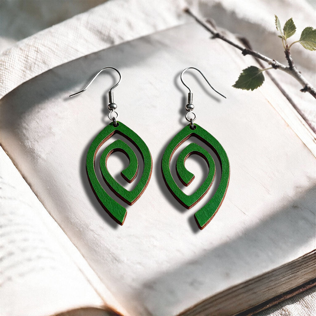 Green Labyrinth plywood earrings made in Finland, photographed on a vintage book in natural sunlight