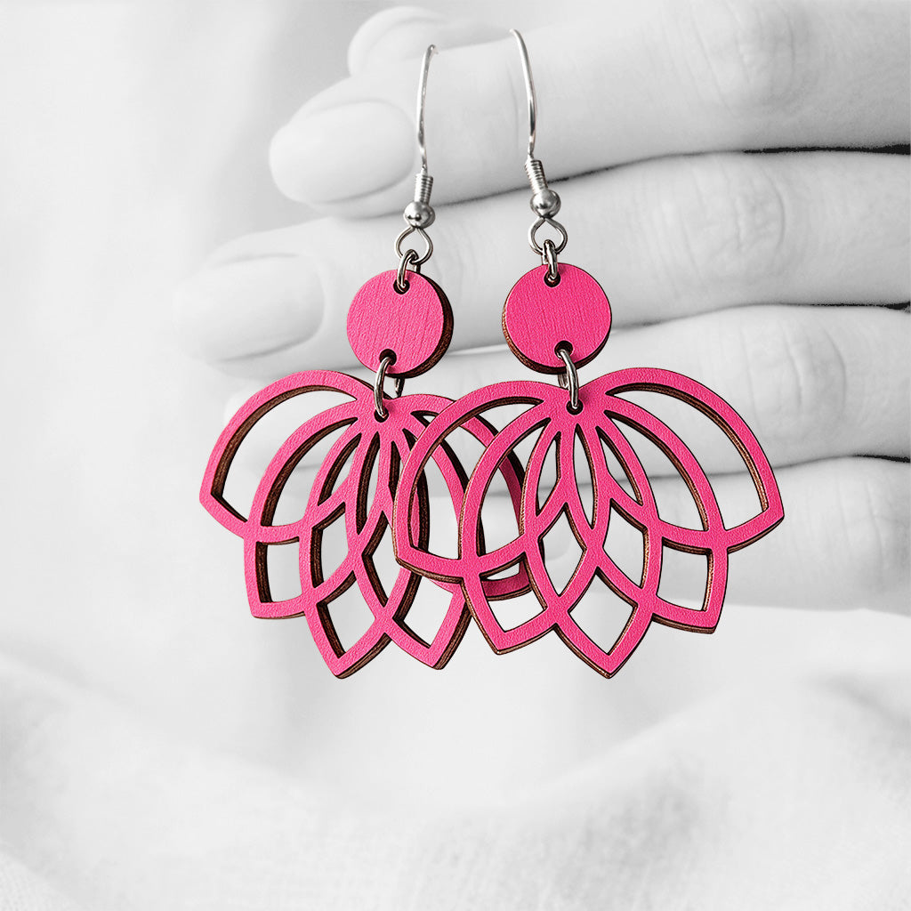 Raspberry plywood earrings made in Finland, photographed on a vintage book in natural sunlight