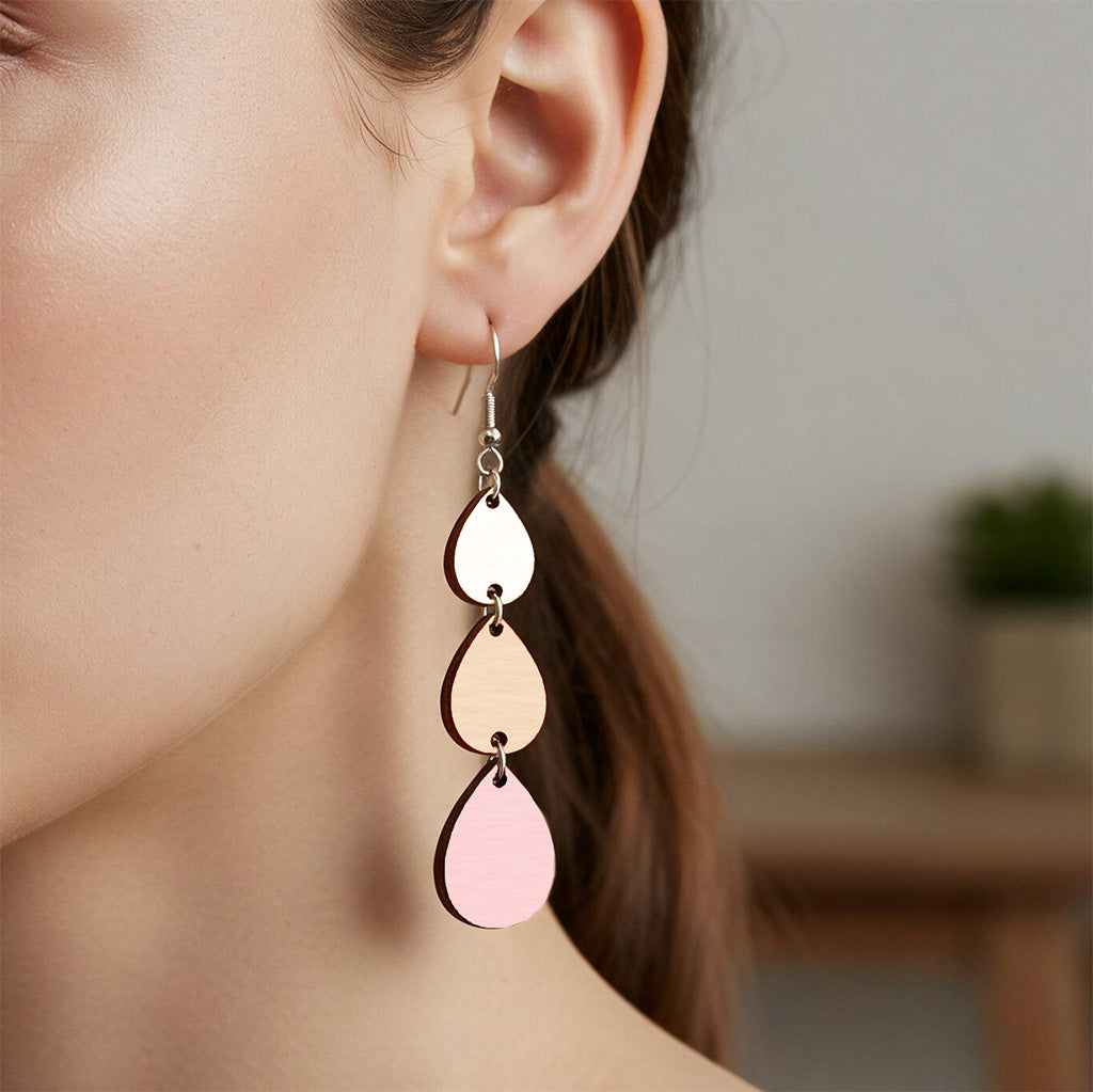 Pink, nude and white Sadetta plywood earring made in Finland, shown worn on the ear to demonstrate size and scale