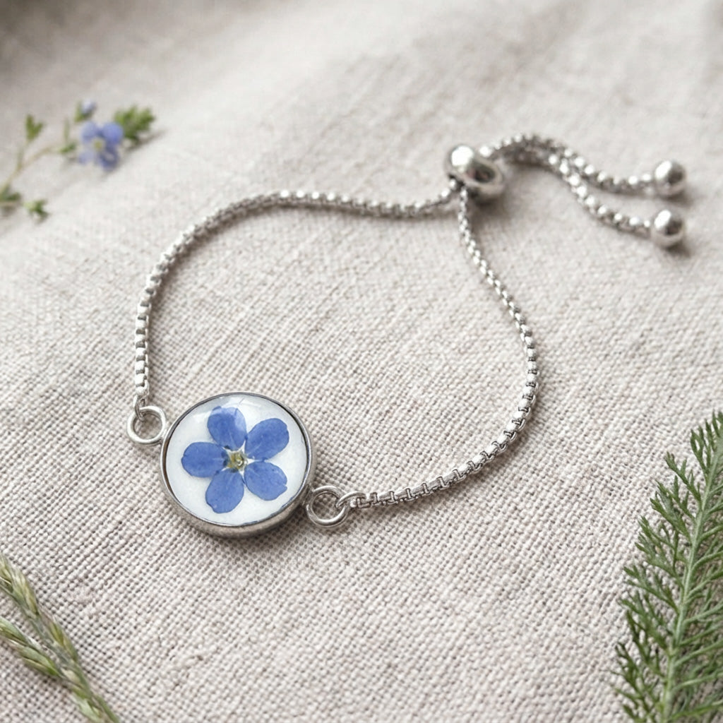 Handcrafted stainless steel bracelet featuring a real forget-me-not flower preserved in clear resin on natural linen. Made in Finland by byMinta.