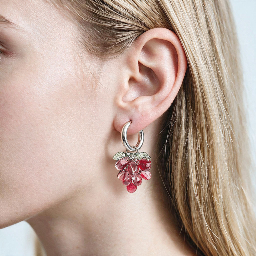 Woman wearing Red Currant Cluster Earrings with translucent red glass beads and stainless steel huggie hoops. Handcrafted in Finland.