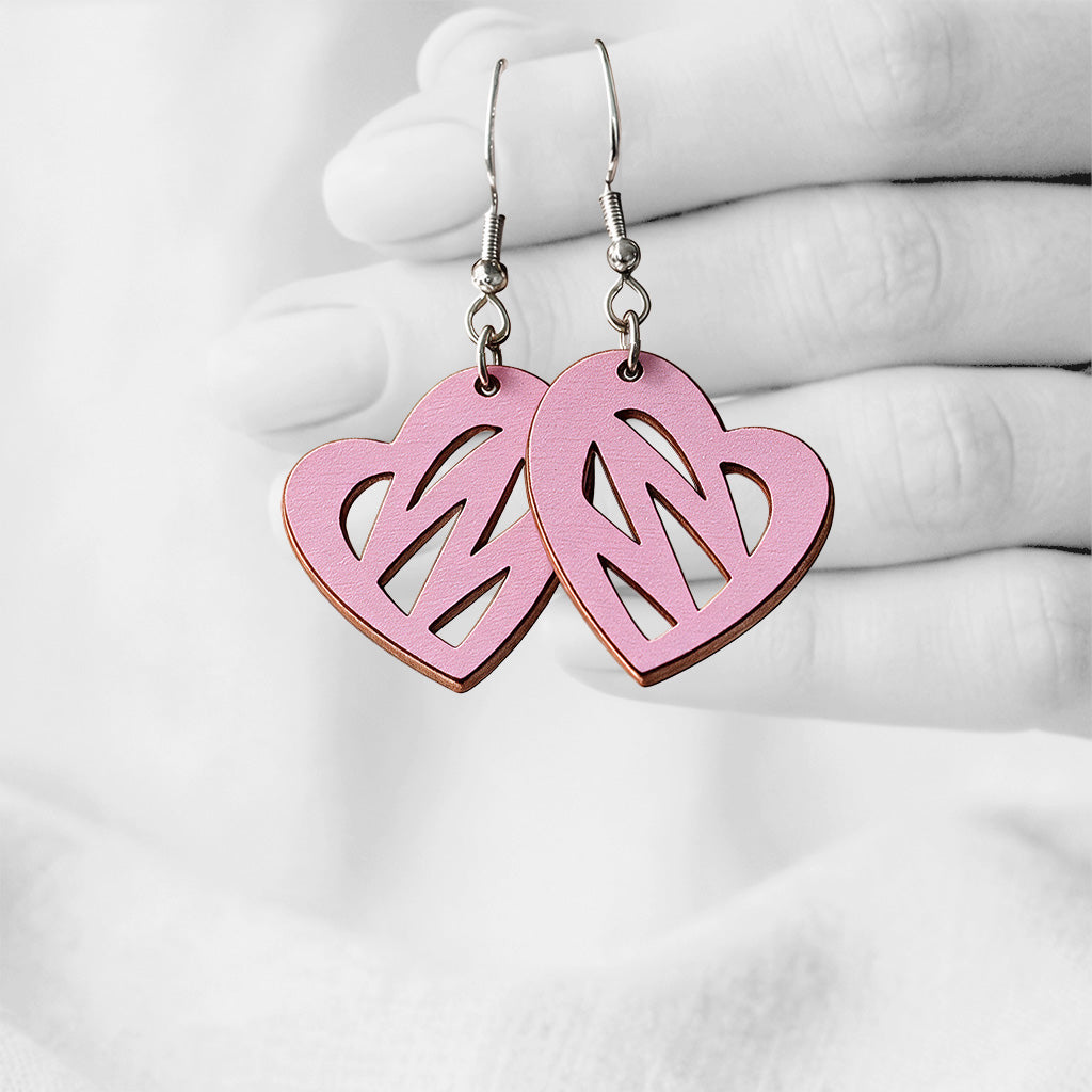 Mauve Syke (Heartbeat) plywood earrings made in Finland, photographed hanging from a hand in black and white against a softly blurred light background.