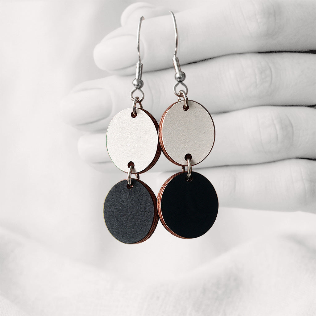 Black and white Tuplakupla duo plywood earrings handmade in Finland, featuring two round wooden pieces on stainless steel hooks