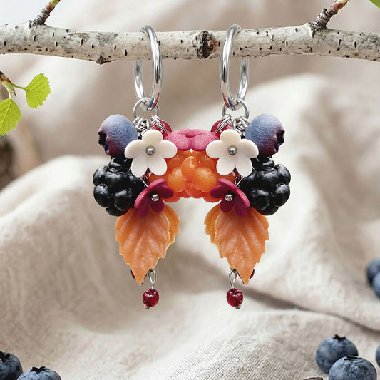 Marjametsä earrings with silver-colored Huggie hoops, photographed on a birch branch in soft natural light