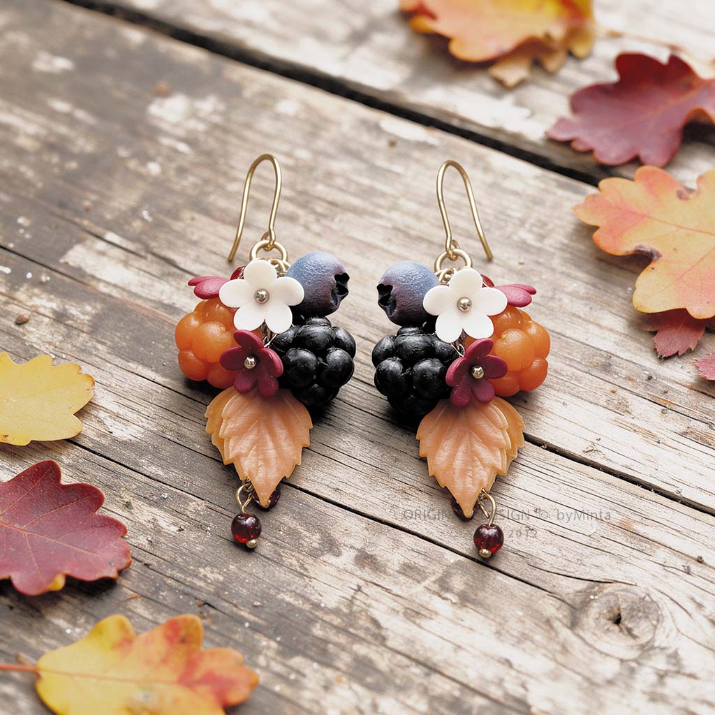 Marjametsä earrings with gold-colored details, handmade in Finland, photographed on a rustic wooden surface with autumn leaves
