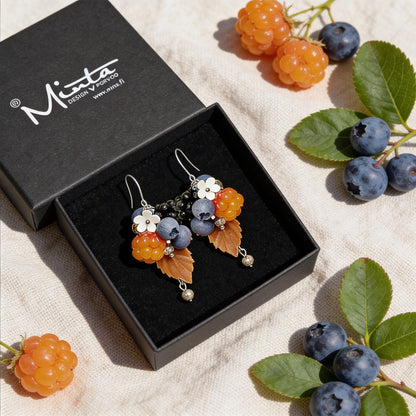 Berry Forest Earrings presented in a gift box, surrounded by natural linen fabric, fresh cloudberries, blueberries, and autum leaves. Handmade in Finland by byMinta.