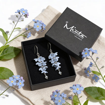 Shadow Vine Earrings presented in a gift box, surrounded by natural linen fabric and delicate blue flowers. Handmade in Finland by byMinta.