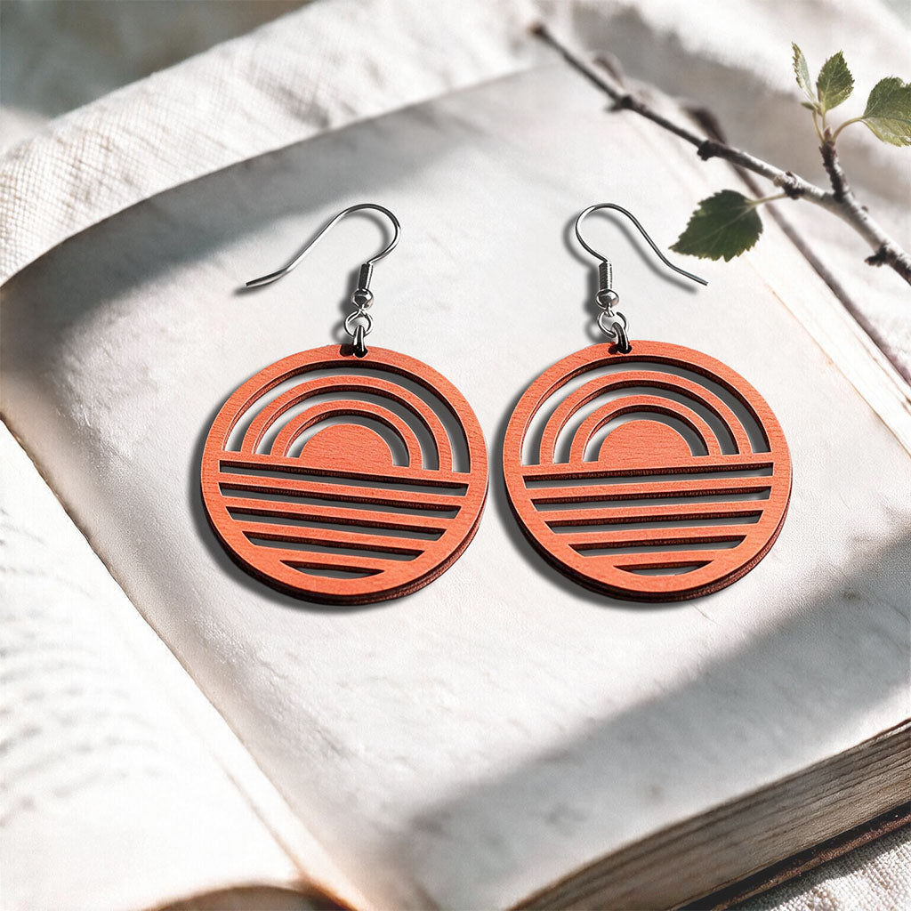Coral Sunrise plywood earrings made in Finland, photographed on a vintage book in natural sunlight