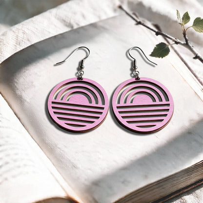 Mauve Sunrise plywood earrings made in Finland, photographed on a vintage book in natural sunlight