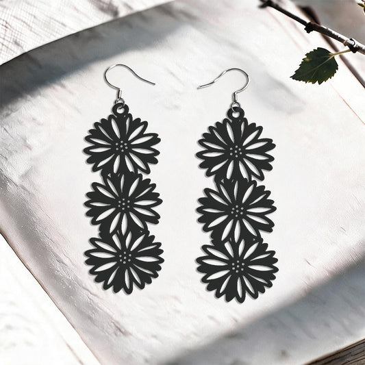 Black Asteria silicone earrings made in Finland, photographed on a vintage book in natural sunlight