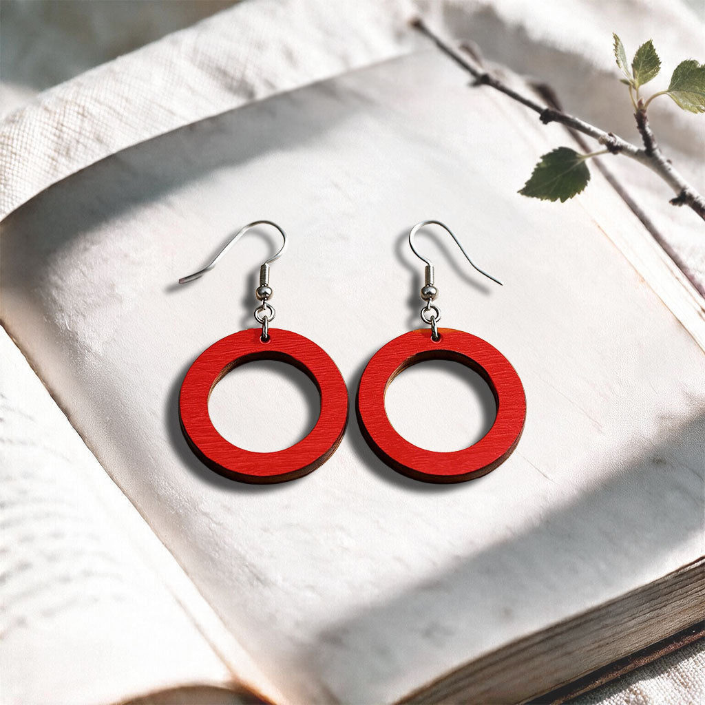 Red Circle plywood earrings made in Finland, photographed on a vintage book in natural sunlight