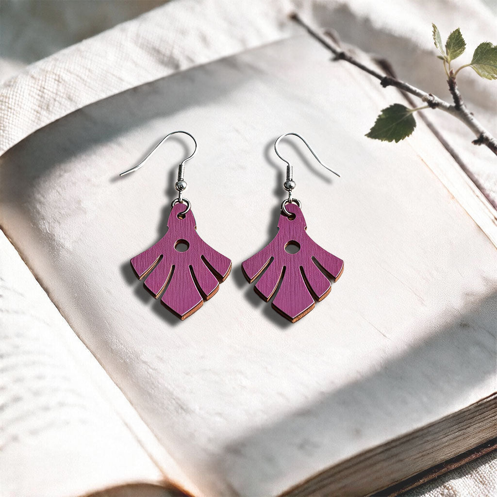 Heather Phoenix plywood earrings made in Finland, photographed on a vintage book in natural sunlight