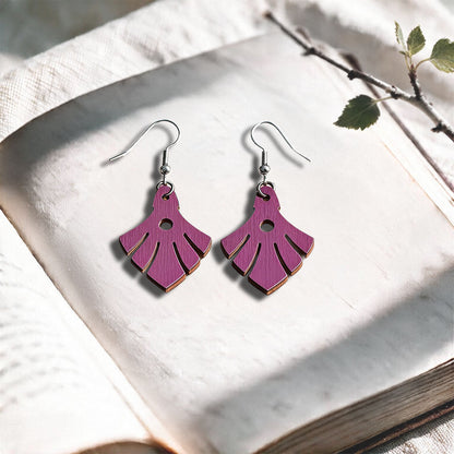 Heather Phoenix plywood earrings made in Finland, photographed on a vintage book in natural sunlight