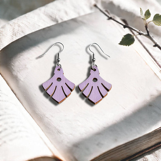 Lavender Phoenix plywood earrings made in Finland, photographed on a vintage book in natural sunlight