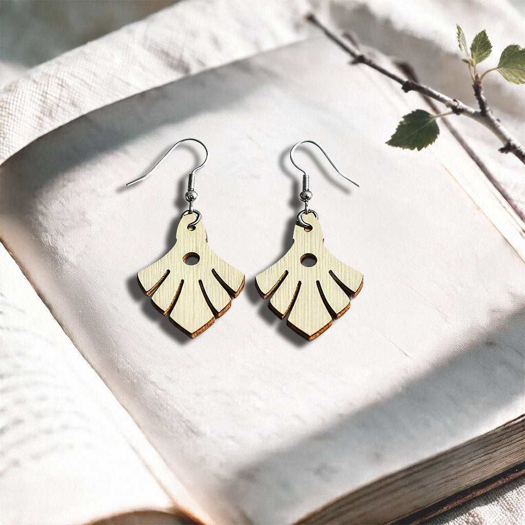 Vanilla Phoenix plywood earrings made in Finland, photographed on a vintage book in natural sunlight