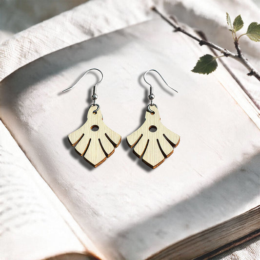 Vanilla Phoenix plywood earrings made in Finland, photographed on a vintage book in natural sunlight