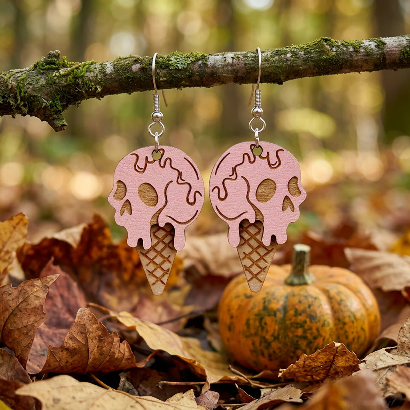 Halloween ice cream earrings hanging from a branch with autumn leaves and a pumpkin.