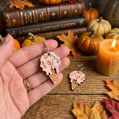 Hand holding Halloween ice cream earrings with skull design, handmade in Finland.