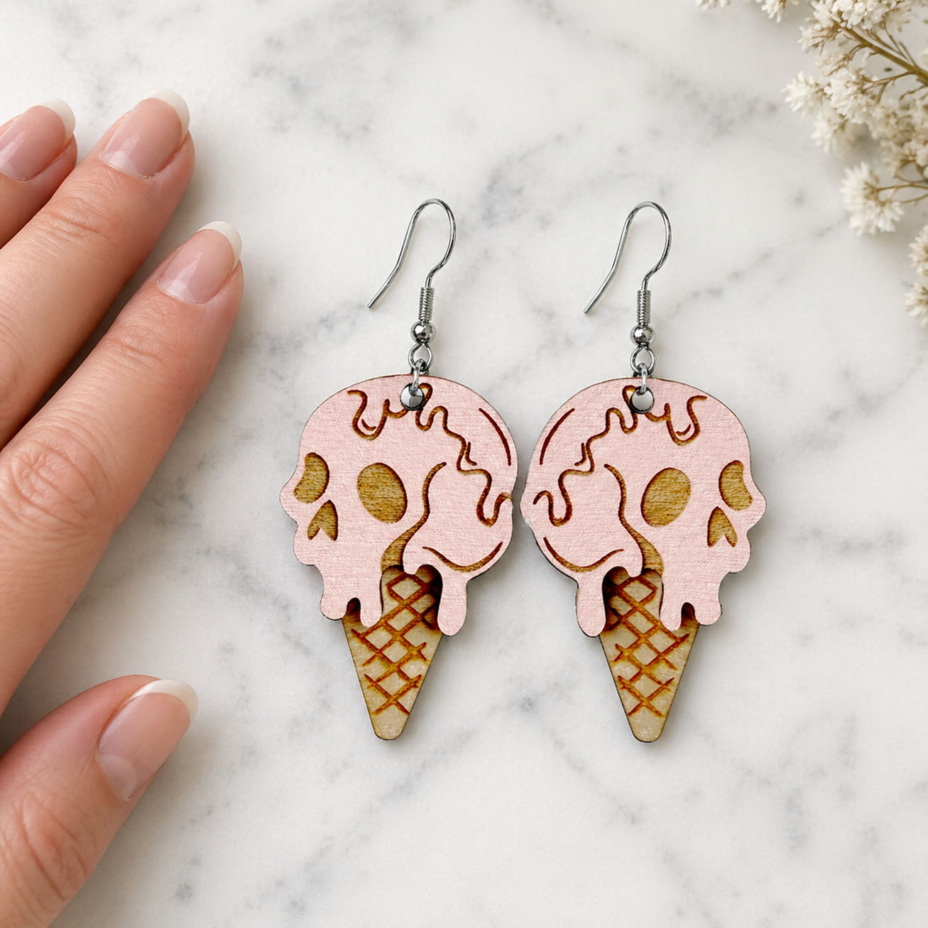 Handmade skull ice cream cone earrings, lightweight wooden jewelry, shown with hand for scale