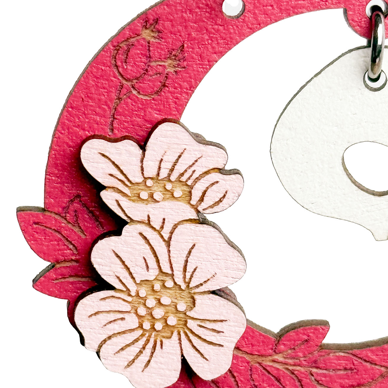 Close-up of skull earrings with pink crescent and flowers, handmade wooden Halloween earrings byMinta