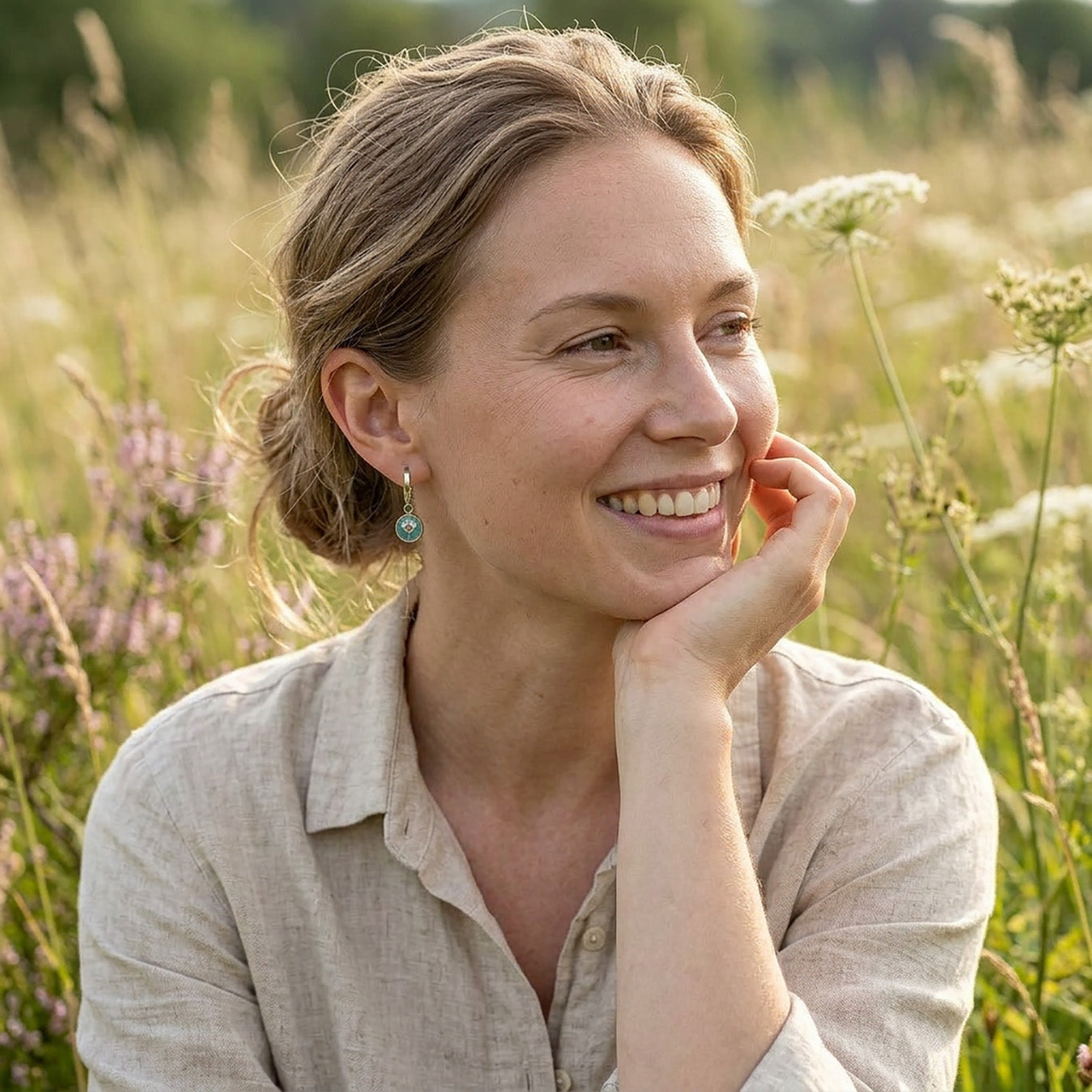 Woman wearing sage green botanical huggie earrings in summer meadow, lightweight handmade flower jewelry