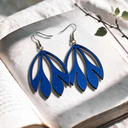 Blue Flutter plywood earrings made in Finland, photographed on a vintage book in natural sunlight