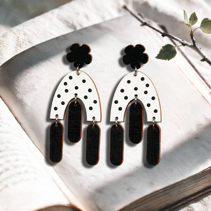 Black and white Swinging Hems plywood earrings made in Finland, photographed on a vintage book in natural sunlight
