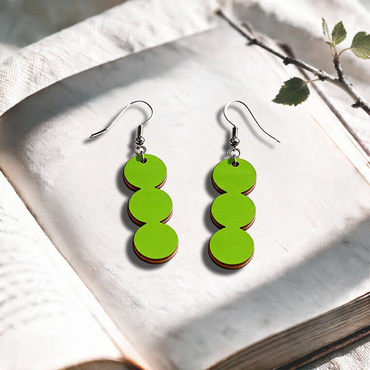 Lime String of Pearls plywood earrings made in Finland, photographed on a vintage book in natural sunlight