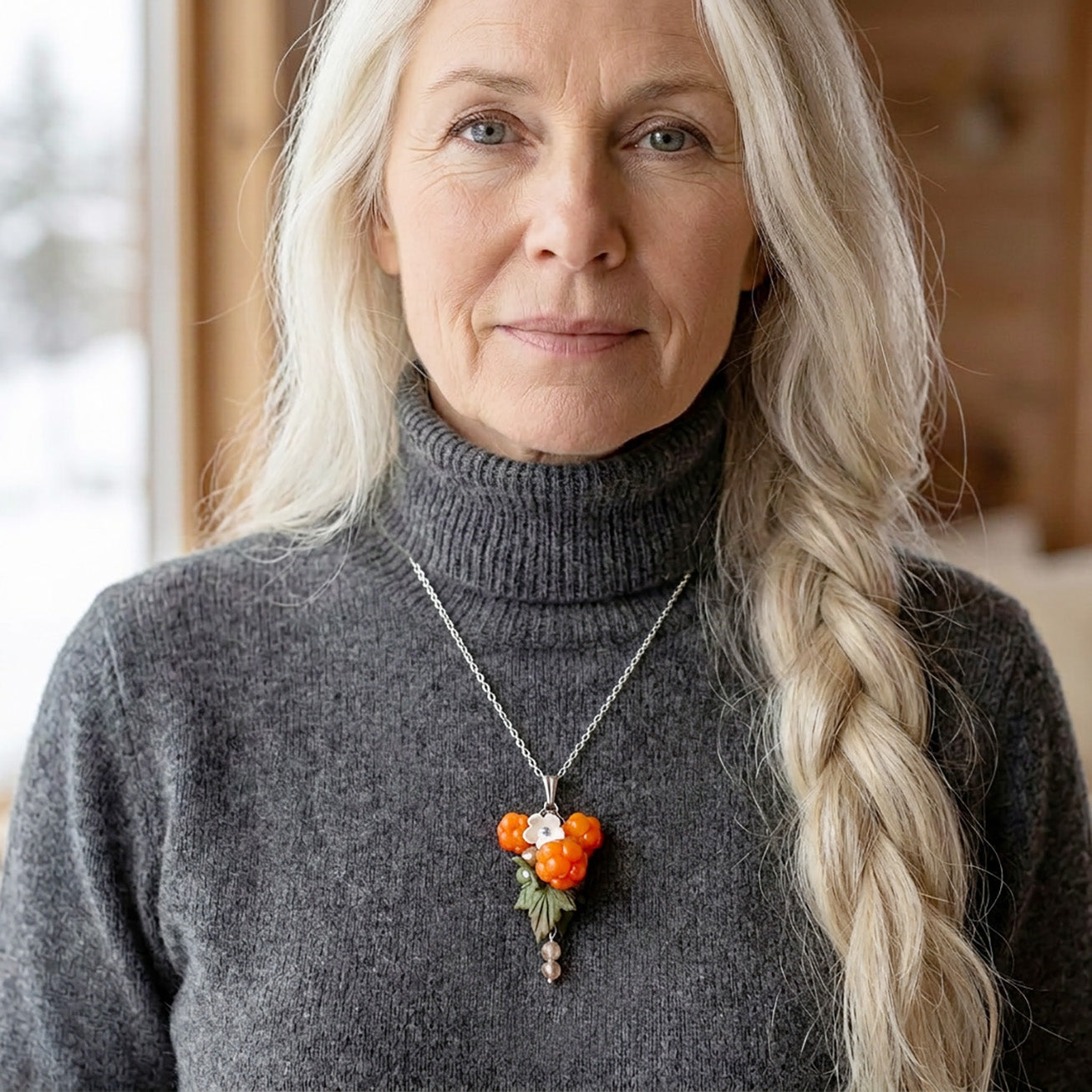 Woman wearing a cloudberry necklace with handmade orange berries and white flowers, Nordic style jewelry, handcrafted in Finland.