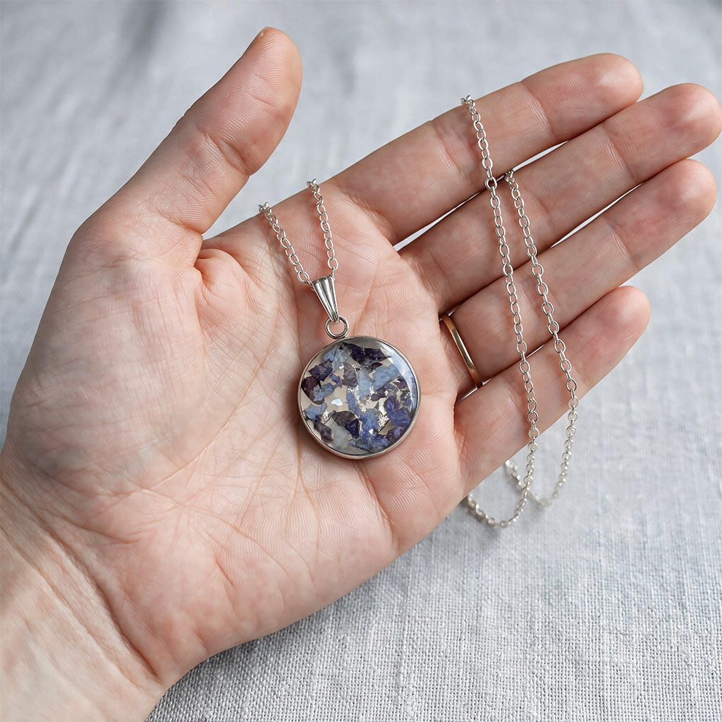 Hand holding handmade hydrangea necklace with real hydrangea flowers preserved in resin