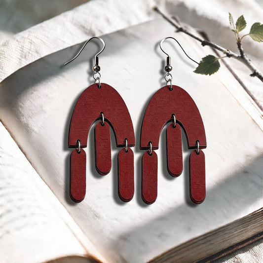 Brown Fluttering Hems plywood earrings made in Finland, photographed on a vintage book in natural sunlight