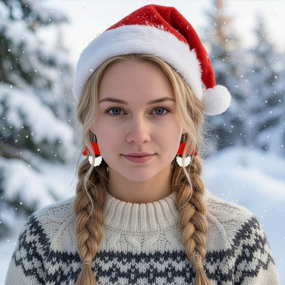 Blonde woman wearing Santa Claus earrings and a red Santa hat in a snowy winter landscape, dressed in a warm Nordic knit sweater. Handmade in Finland by byMinta.