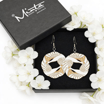 Handmade light wood statement earrings displayed in a black jewelry gift box surrounded by delicate white flowers. Bright soft natural light, elegant Nordic style product photography with airy and romantic atmosphere.