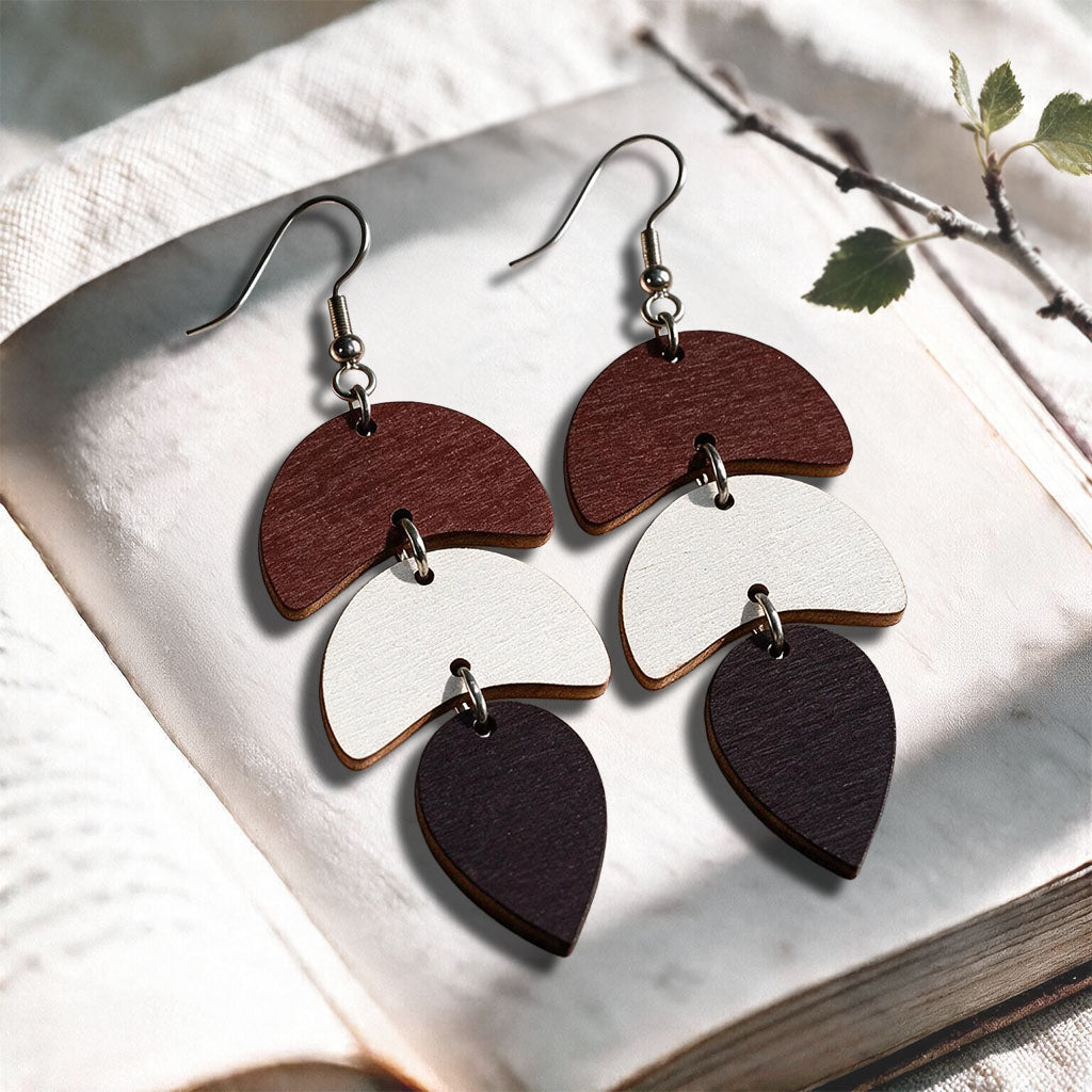 Brown white and dark brown Echo plywood earrings made in Finland, photographed on a vintage book in natural sunlight