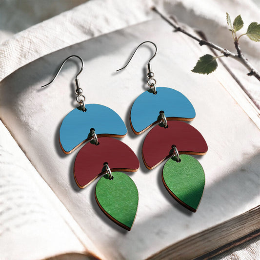 Green, rust and skyblue Echo plywood earrings made in Finland, photographed on a vintage book in natural sunlight