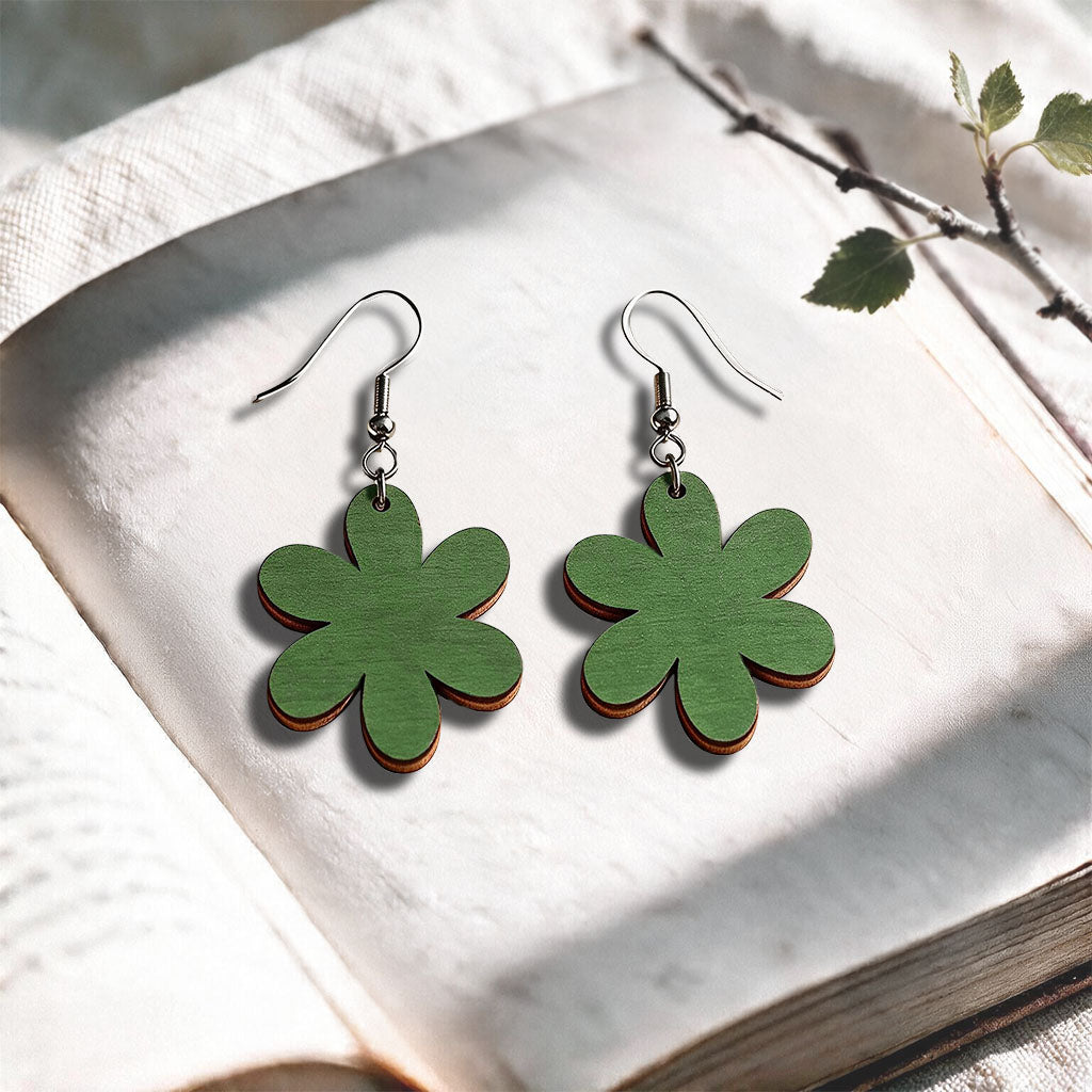 Moss green plywood earrings made in Finland, photographed on a vintage book in natural sunlight