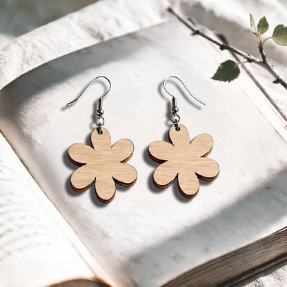 Birch plywood earrings made in Finland, photographed on a vintage book in natural sunlight