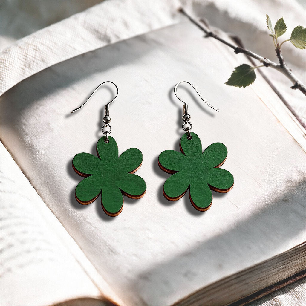 Green plywood earrings made in Finland, photographed on a vintage book in natural sunlight