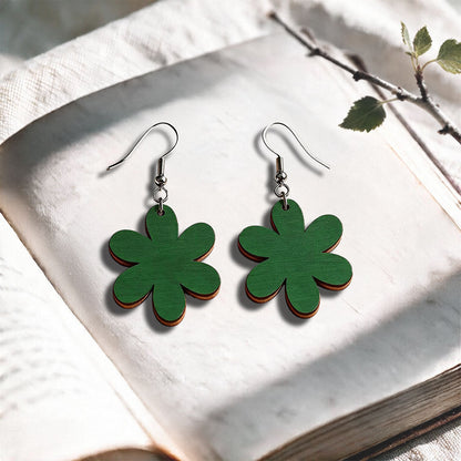 Green plywood earrings made in Finland, photographed on a vintage book in natural sunlight