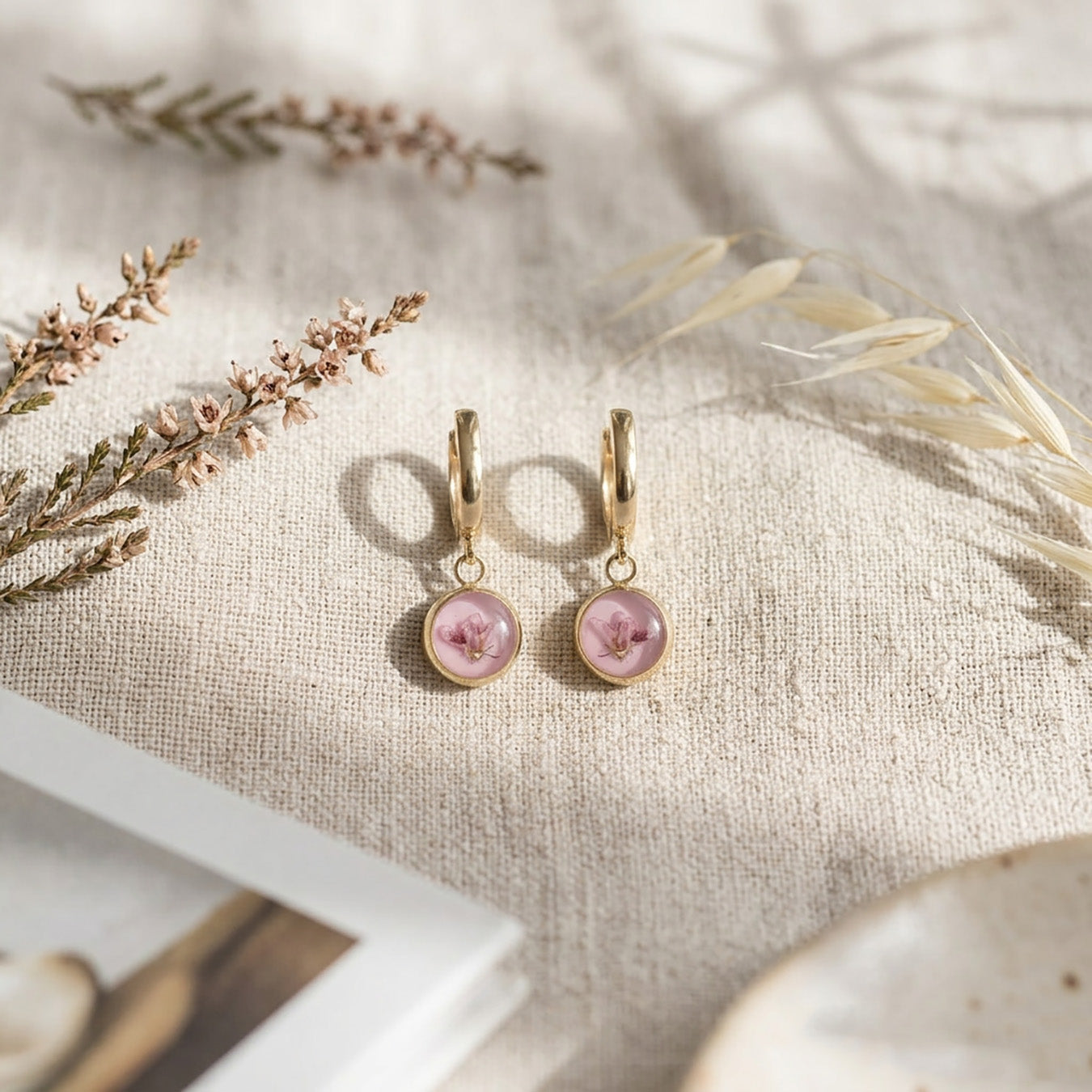 Pink heather flower huggie earrings on linen fabric with dried flowers, handmade Finnish jewelry