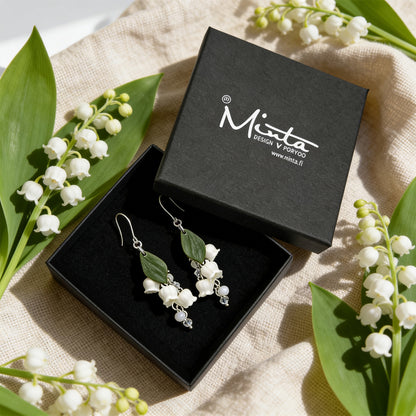 Lily of the Valley Earrings presented in a gift box, surrounded by natural linen fabric and fresh lily of the valley flowers. Handmade in Finland by byMinta.