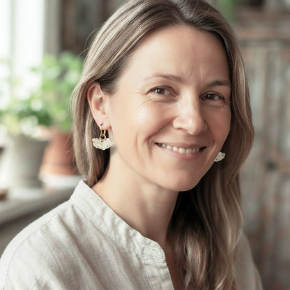 Woman wearing Bloom Meringue glass flower earrings with gold huggie hoops, handcrafted in Finland by byMinta