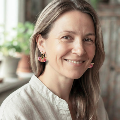 Woman wearing Bloom Sorbet glass flower earrings with gold huggie hoops, handcrafted in Finland by byMinta