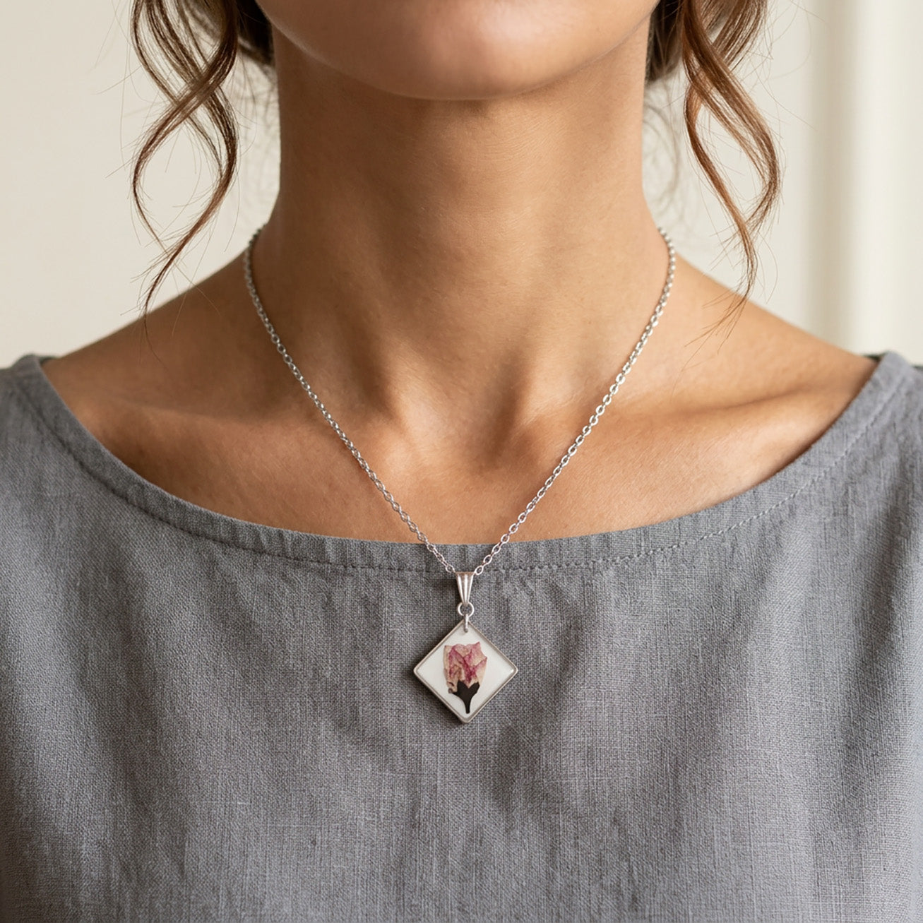 Woman wearing delicate cherry blossom necklace with stainless steel chain and real flower pendant