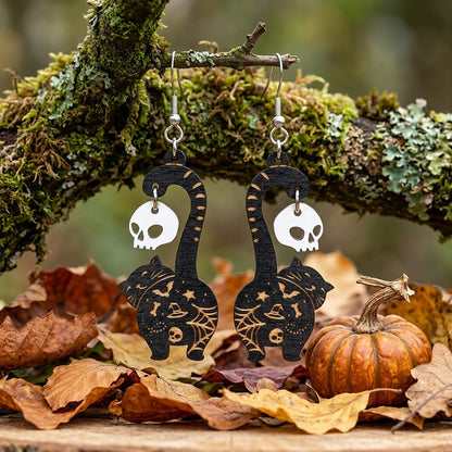 Black cat earrings with skull charms hanging on a branch, handmade Halloween earrings from Finnish birch plywood.