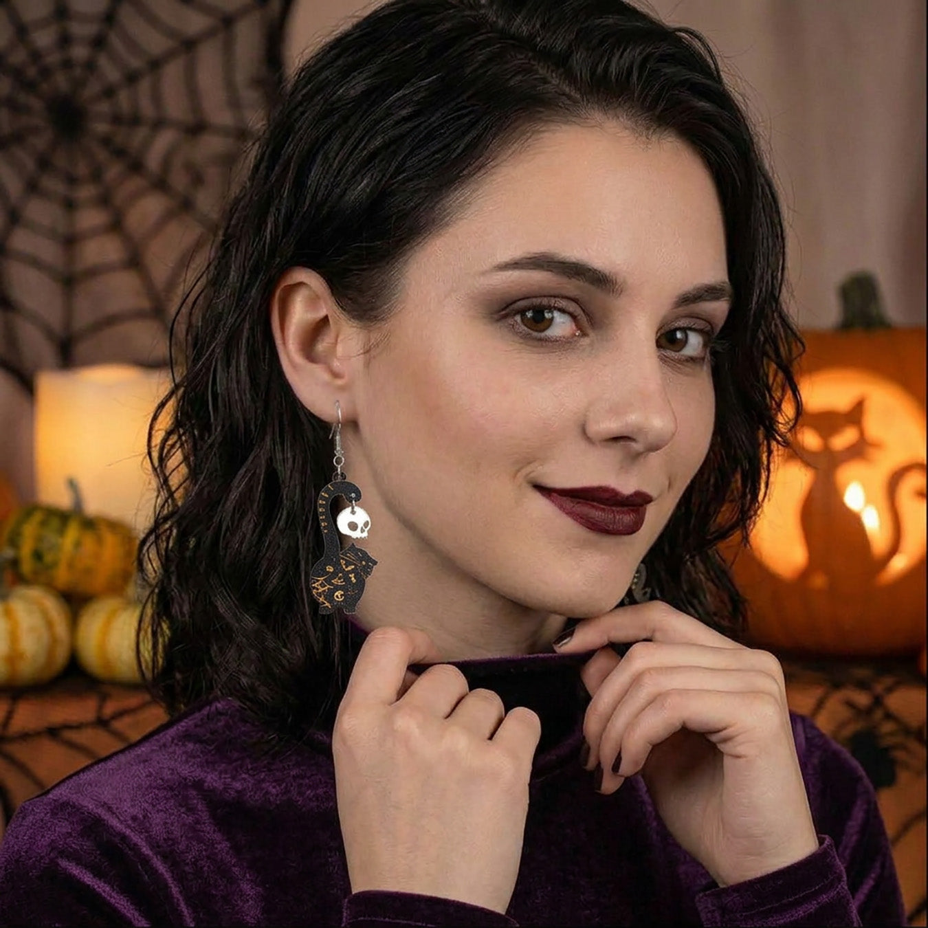 Black cat earrings with skull charms worn by a model, lightweight handmade Halloween earrings.